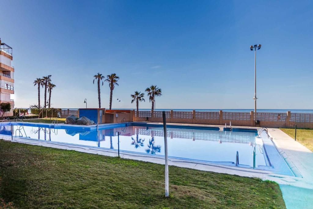 a large swimming pool with palm trees and the ocean at A&N Pueblo Bahia in Algarrobo-Costa