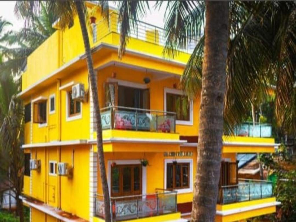 ein gelbes Gebäude mit Palmen davor in der Unterkunft Villa platinum 4 BHK Calangute in Calangute