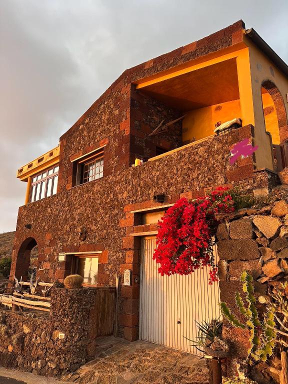 a brick building with a garage with red flowers on it at Casa El Sato in Echedo