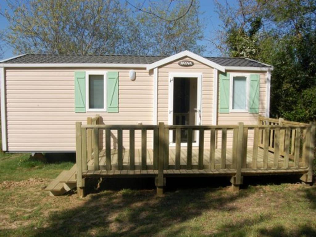 a small white house with a wooden porch at Mobil Home Confort 2 Chambres avec Terrasse - API-1-52-347 in Rives