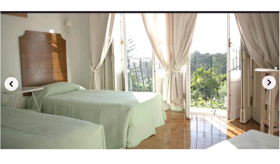 um quarto com duas camas e uma grande janela em Monte da Lua em Sintra