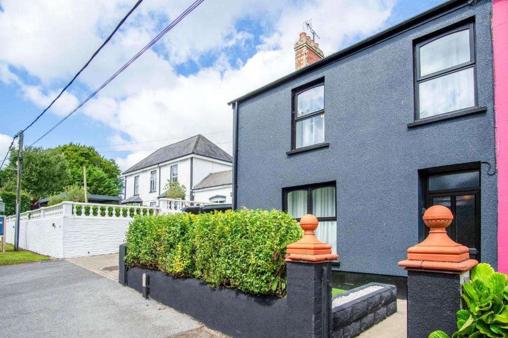 une maison bleue avec des buissons devant elle dans l'établissement No 7 Moorfield Road - 3 Bed Townhouse - Narberth, à Narberth