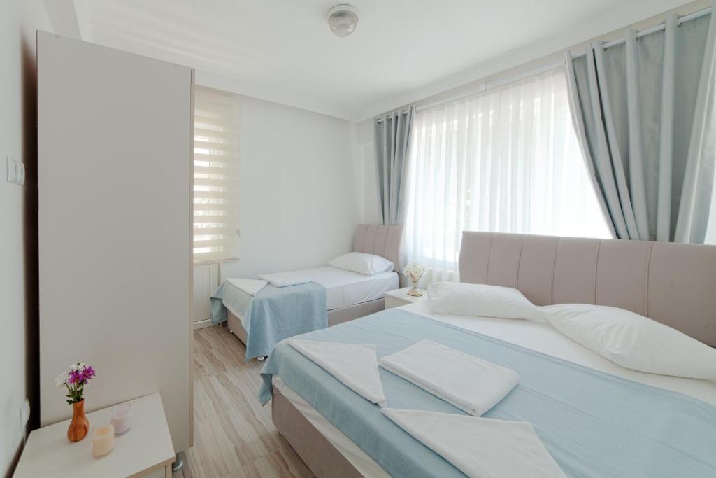 a bedroom with two beds and a large window at Hotel Tuna in Akçay