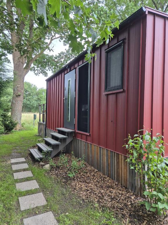 a red tiny house with stairs next to a tree at Chalet Stockholm in Bleckede