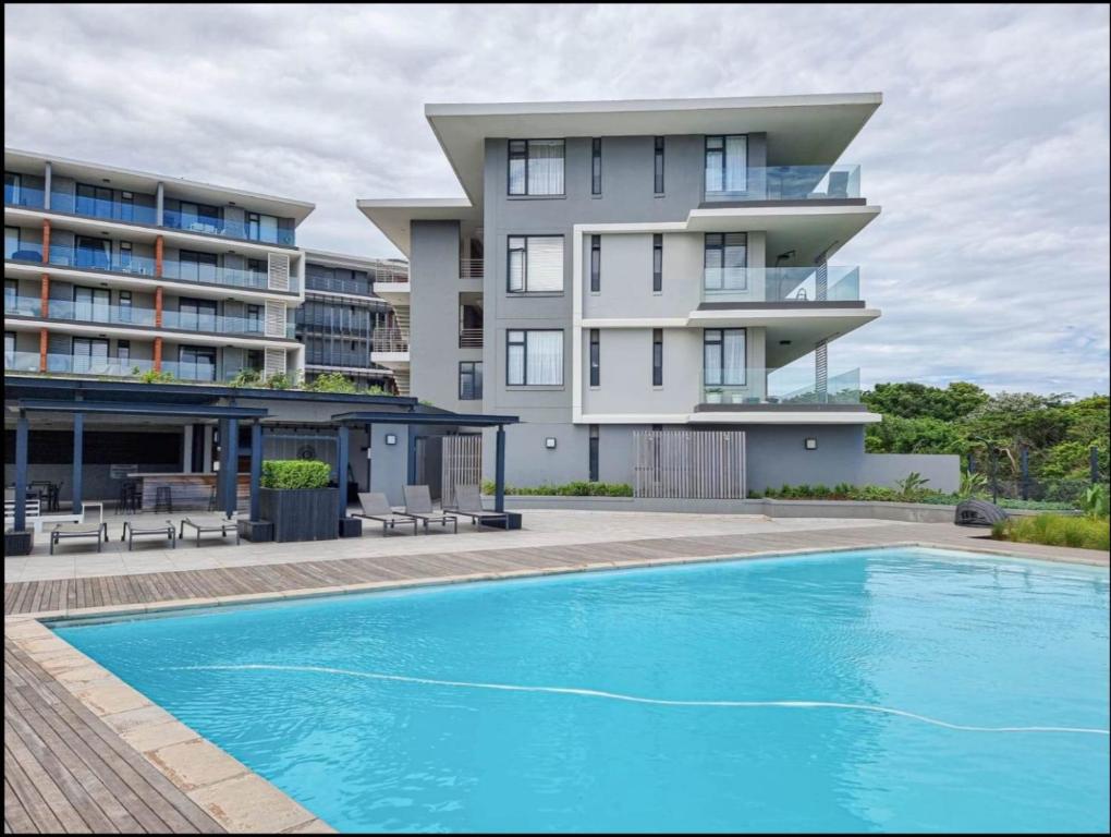 a building with a swimming pool in front of a building at Exclusive Two Bedrooms Presidential Suite in Coral Point in Sibaya