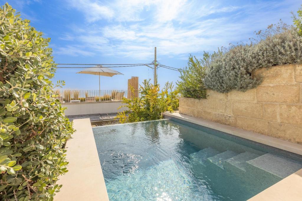 een zwembad naast een muur met een parasol bij Appartamento Marinaia Panorama in Marittima