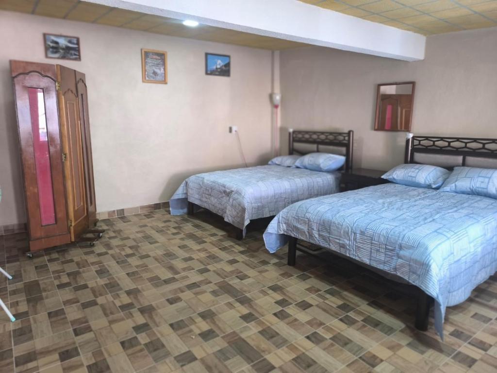 een hotelkamer met twee bedden en een deur bij Adelita in Atlixco