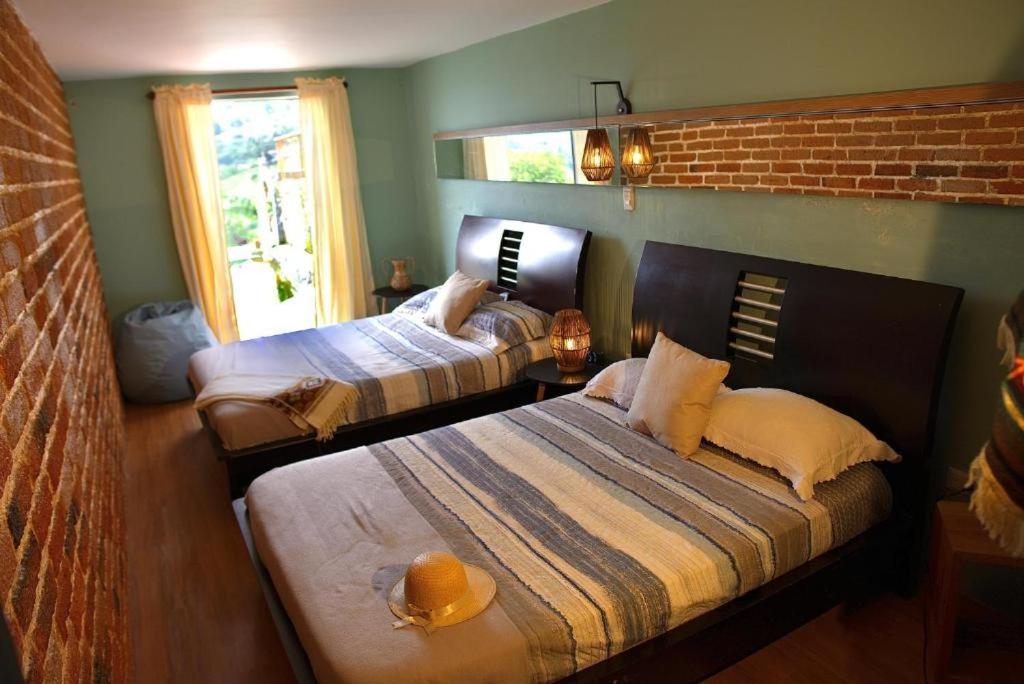 a bedroom with two beds and a brick wall at Casa Grande Coffee House in El Guayabo