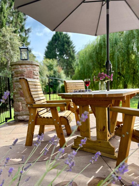 a wooden table and chairs with an umbrella on a patio at Flurry's Lodge in Coleford