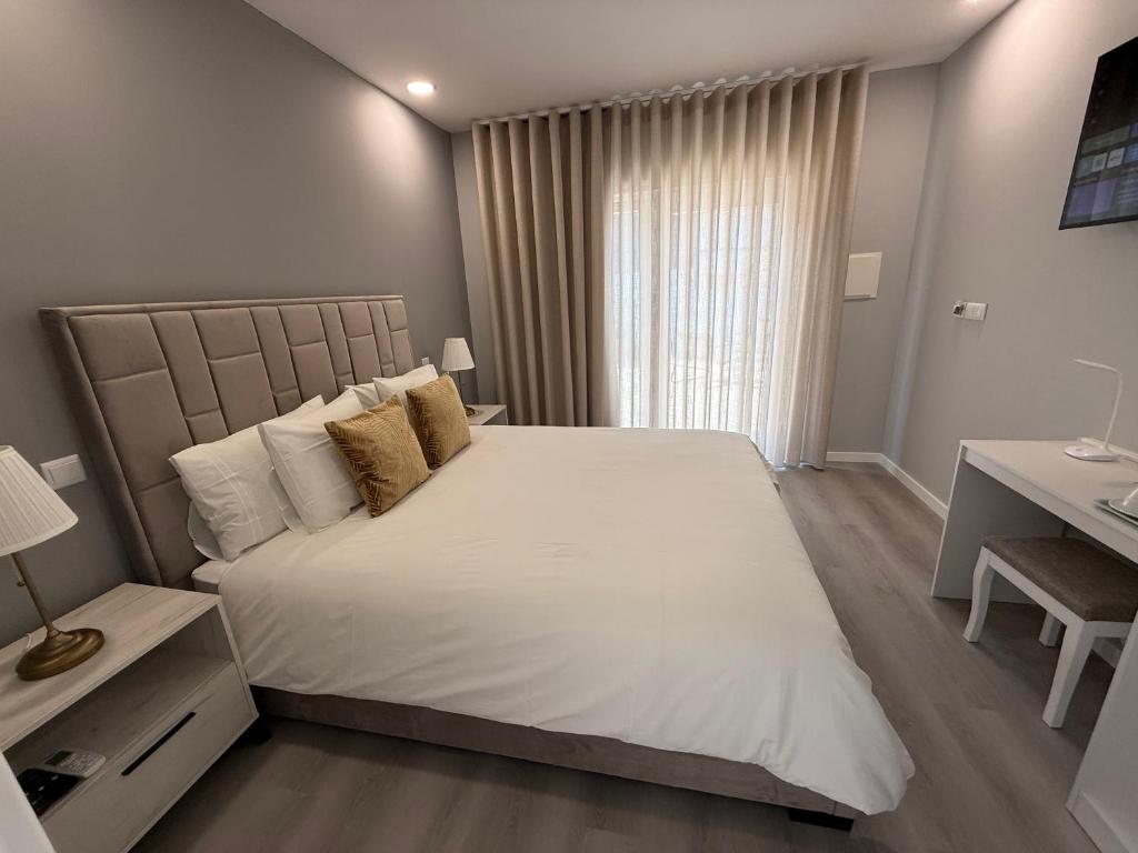a bedroom with a large white bed and a desk at Alfatima in Manteigas
