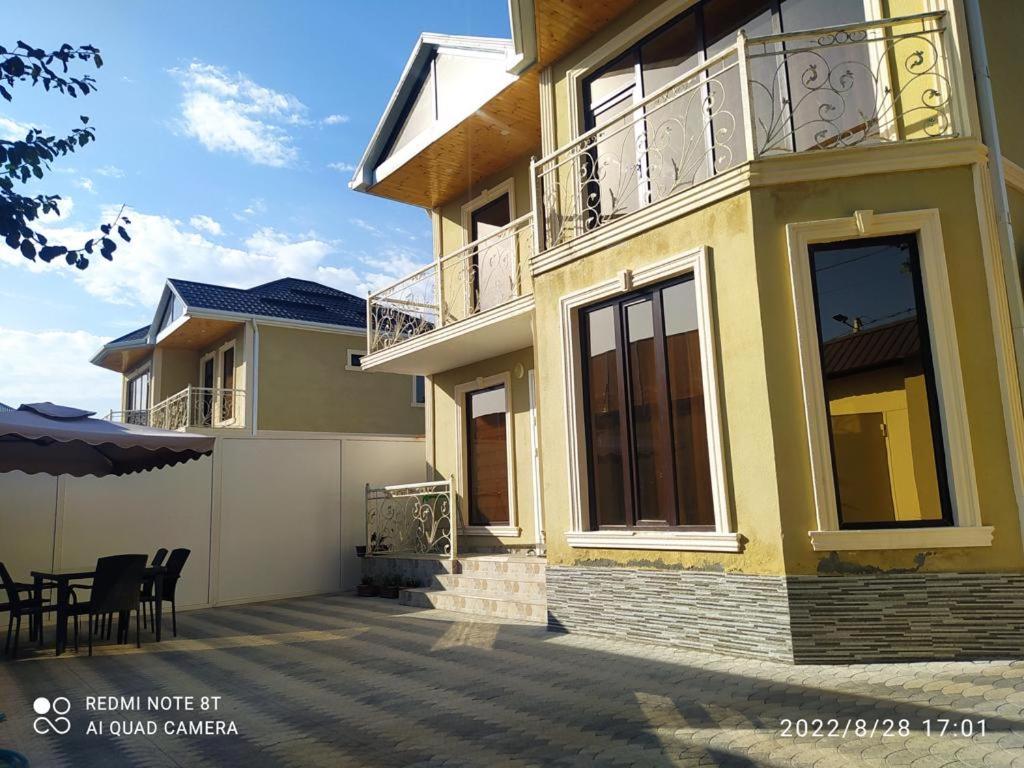 een geel huis met een balkon en een patio bij Villa Vip in Gabala