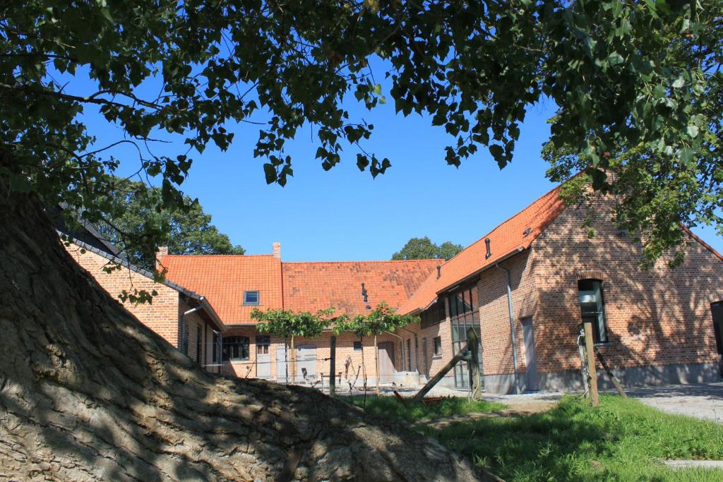 an old brick building with a red roof at De Maalderie Holiday Home in Houthulst