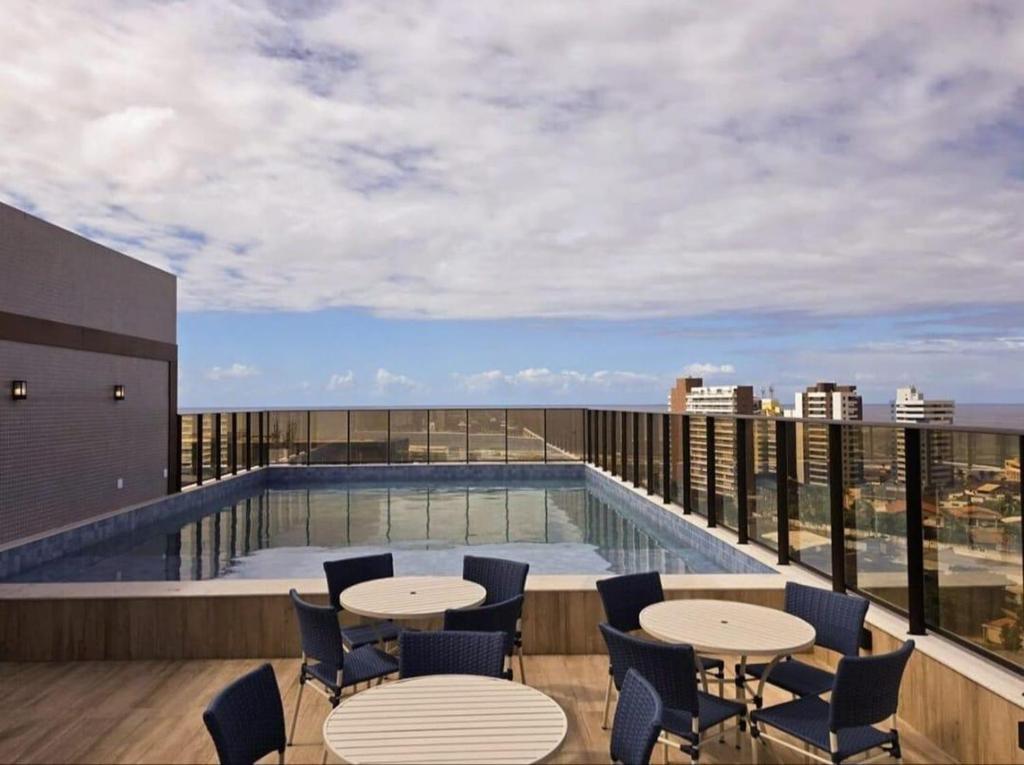 un balcón con mesas y sillas y una piscina en NOVO frente ao Mar - 750m da Orla e Pq dos Ventos - Oceanfront - 3 Guests, en Salvador