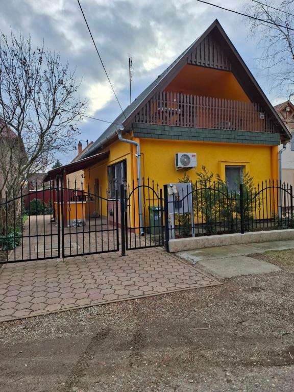a yellow house with a fence in front of it at Fenyves Nyaraló in Hajdúszoboszló