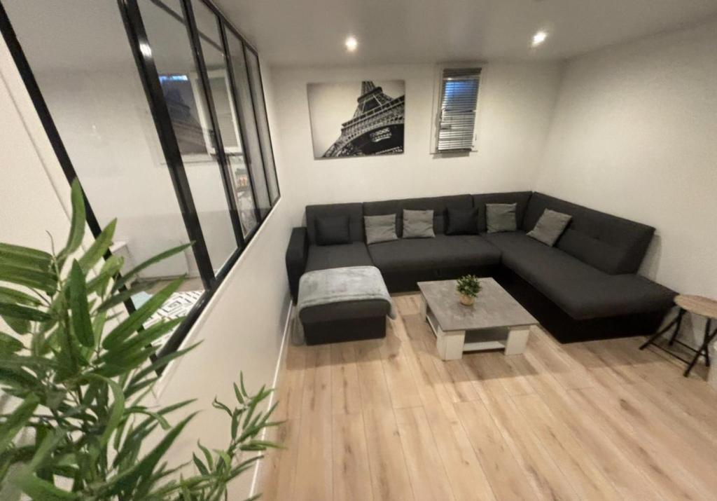 a living room with a black couch and a table at B0 Appart 2022 - 10min PARIS/EXPO - 5 rooms/6 beds in Bagneux