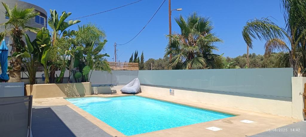 a swimming pool in a backyard with palm trees at Chania Olive Home in Kato Daratso