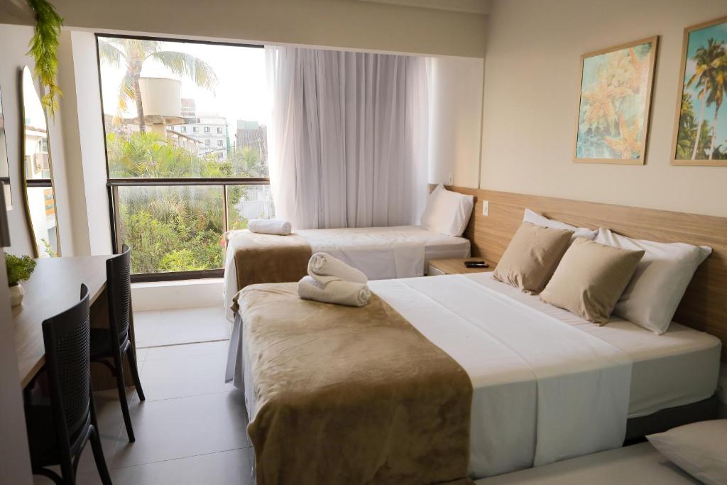 a hotel room with two beds and a window at ORA Beach Residence by AFT in Porto De Galinhas