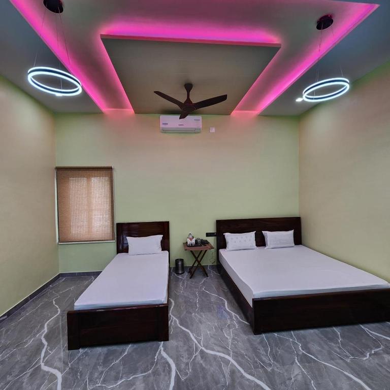 two beds in a room with a ceiling with pink lights at Kanha Hotel and Restaurant in Jāmb