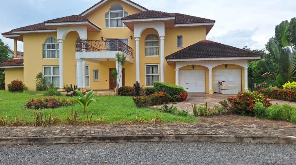 a large yellow house with two garage at Zoey Casa in Accra