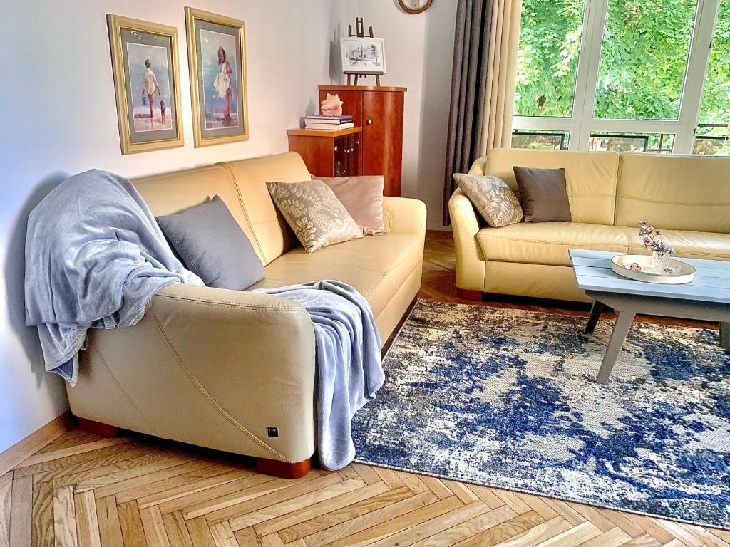 a living room with a couch and a table at Wielki Błękit Apartament z salonem i dwiema sypialniami in Giżycko