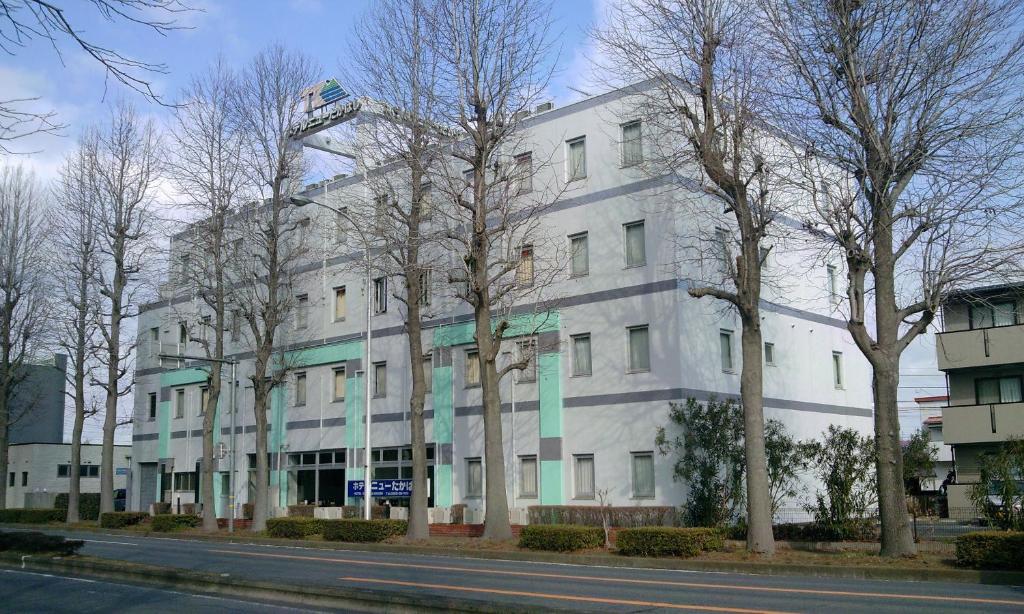 un edificio blanco con árboles delante de él en Hotel New Takahashi Kouyadai, en Tsukuba