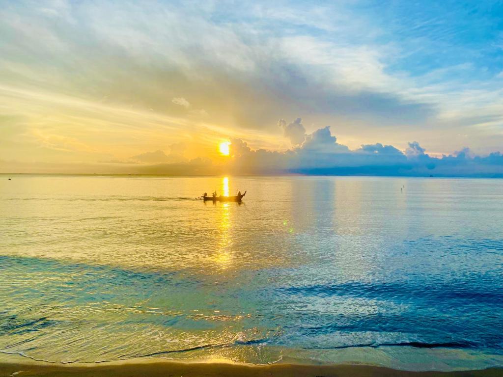 ein Boot mitten im Wasser bei Sonnenuntergang in der Unterkunft Leelavadee Villa Sea Views in Tha Sala