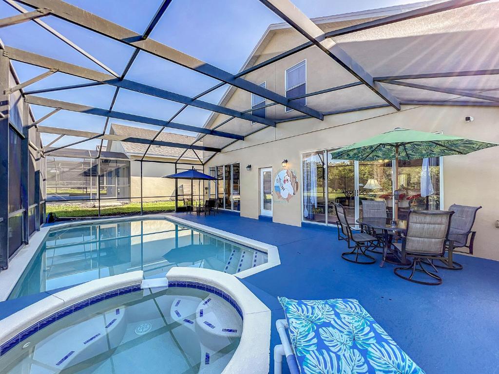 einen Pool mit einem Tisch, Stühlen und einem Sonnenschirm in der Unterkunft Villa near Disney w pool, spa & game room in Orlando