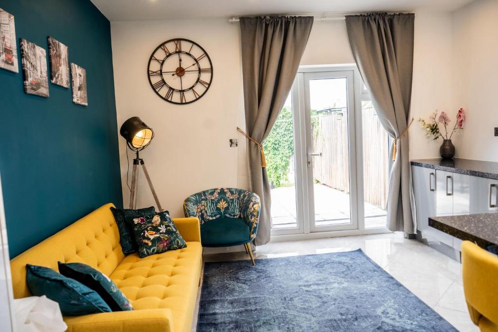 sala de estar con sofá amarillo y reloj en la pared en Delightful 1-Bedroom Apartment with Garden, en South Norwood