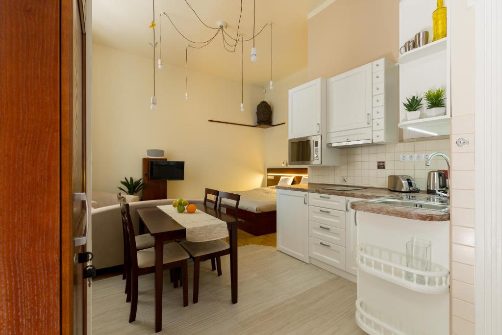 ブダペストにあるFamily Buddha Apartmentの白いキャビネット、テーブルと椅子付きのキッチンが備わります。