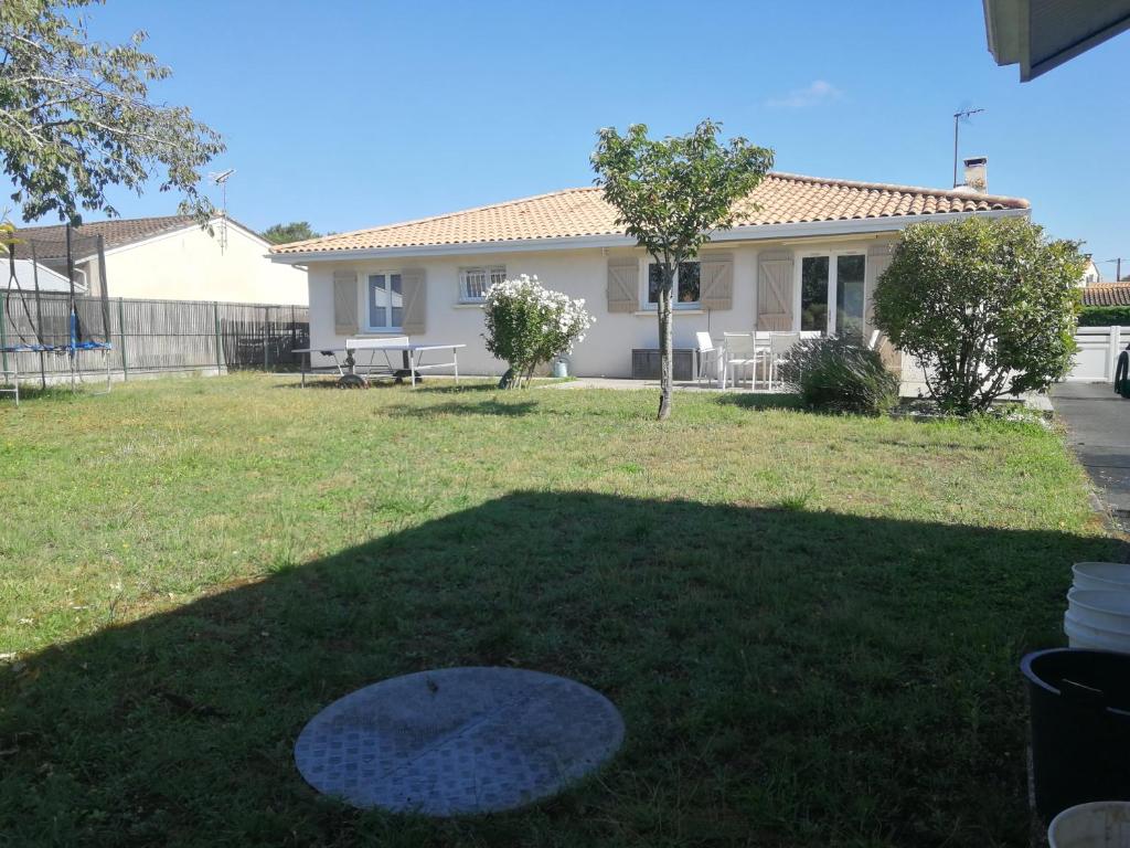 a yard with a house in the background at Maison privée 106m2 avec 3 chambres et jardin in Saint-Médard-en-Jalles