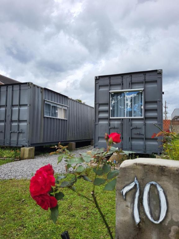 una casa negra con flores rojas delante en Canela Container, en Canela
