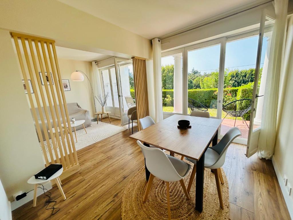 ein Esszimmer mit Tisch und Stühlen und ein Wohnzimmer in der Unterkunft Villa del mare jardin privatif parking privé in Trouville-sur-Mer