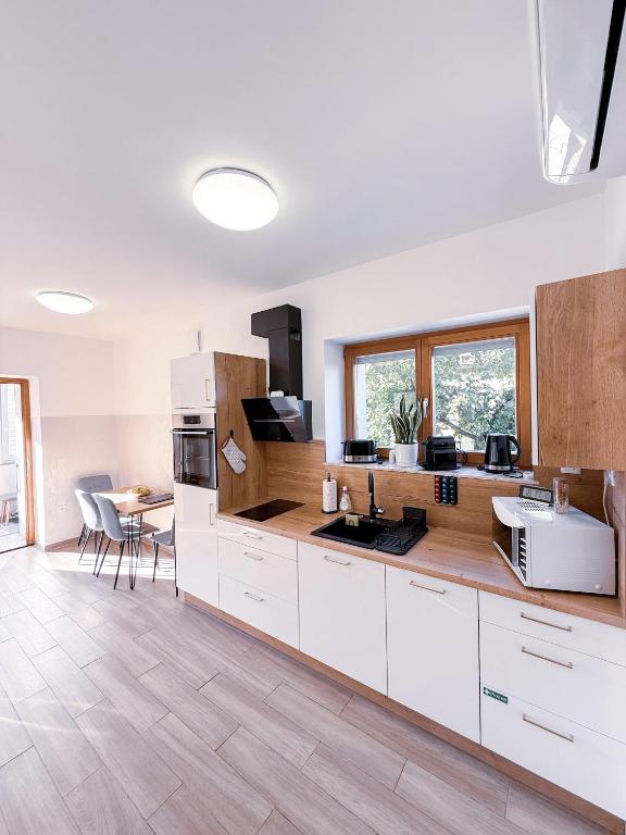 a kitchen with white cabinets and a table with chairs at L Apartment II in Maribor