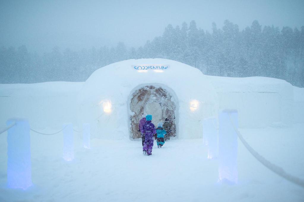 a person standing in front of an igloo in the snow at Sorrisniva Igloo Hotel in Alta