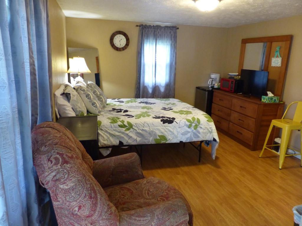 a bedroom with a bed and a chair and a couch at Charming Country 1Bd 1Ba Cabin near Eureka Springs, Beaver Lake and White River in Eureka Springs