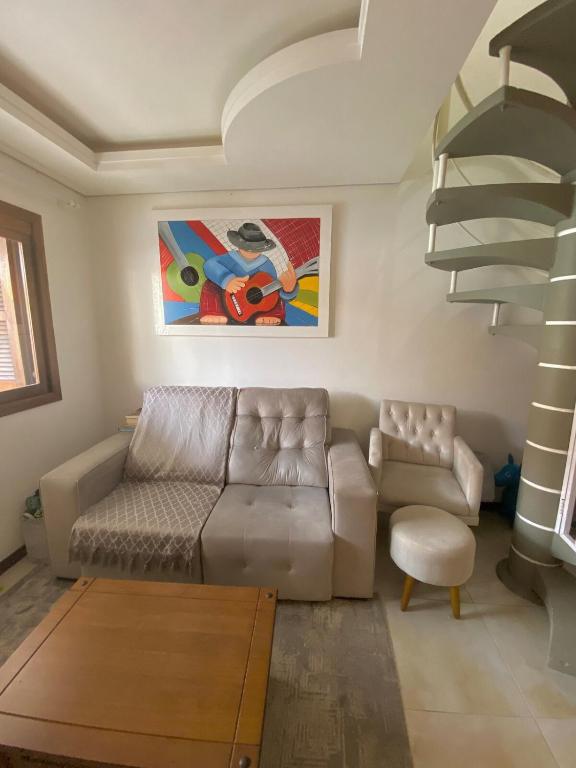 a living room with a couch and a spiral staircase at Duplex Acolhedor - Duas quadras do Mar Centro in Tramandaí