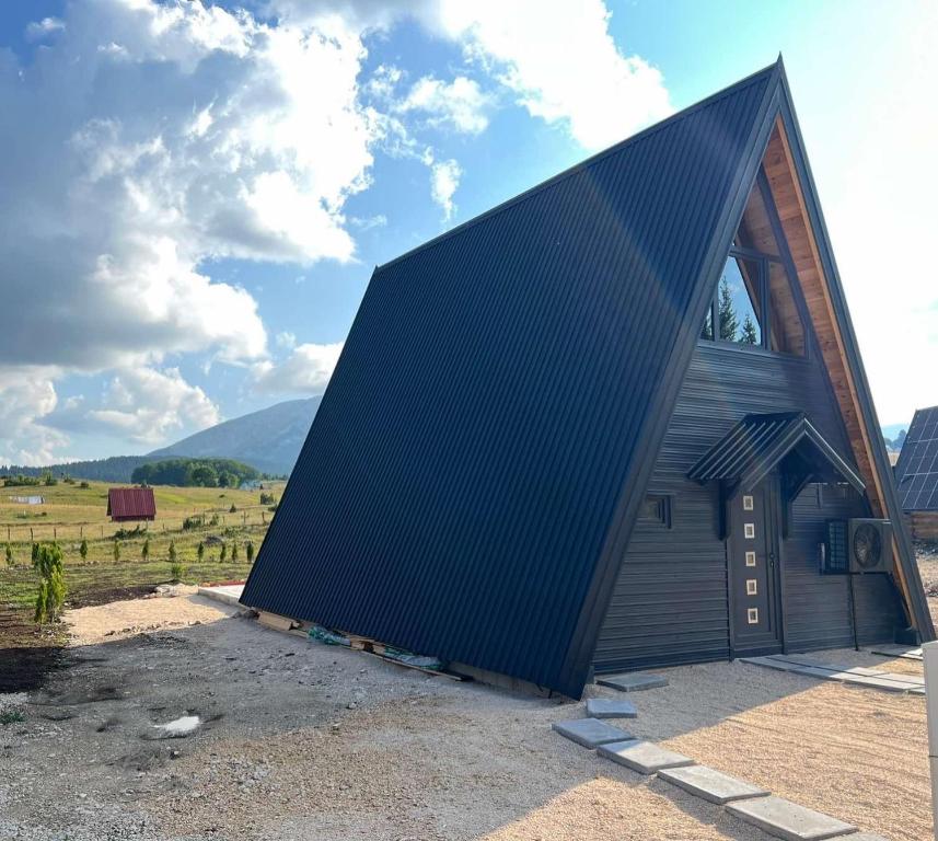 a large black roofed building with a field in the background at Vista Montis in Žabljak