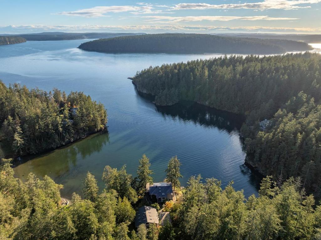 an island in the middle of a lake with a house at Waterfront Privacy, Hot Tub, Mooring, Gated Estate in Eastsound