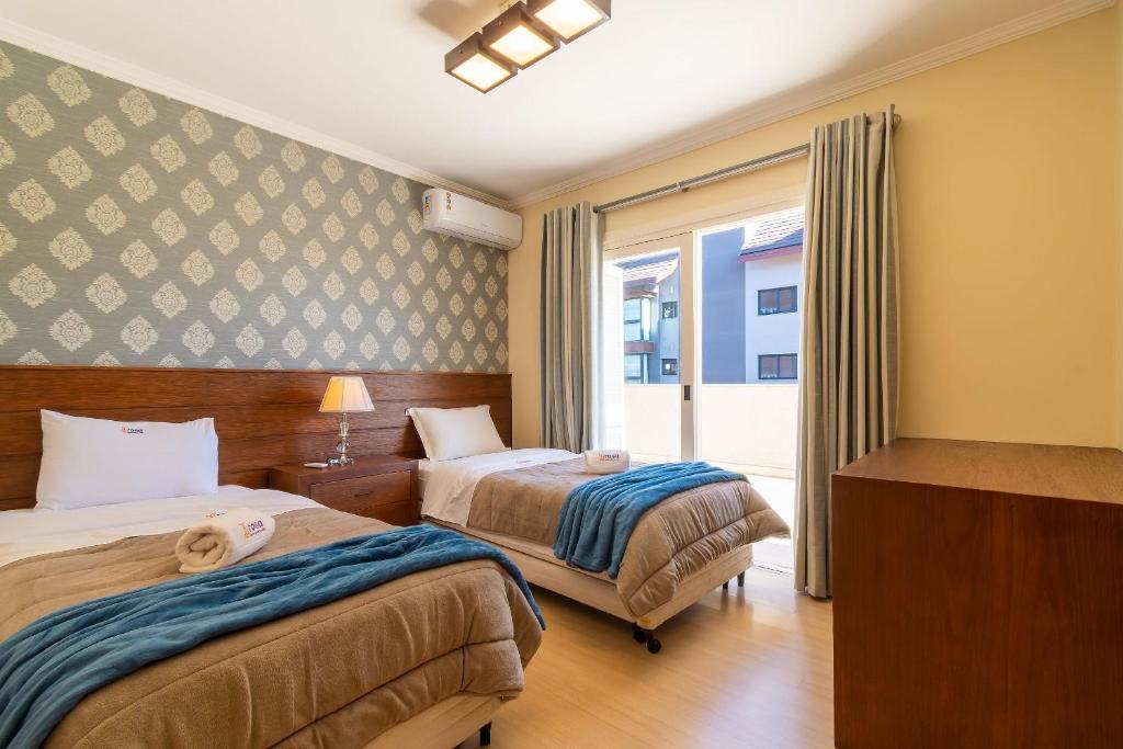 Una habitación de hotel con dos camas y una ventana. en Rosa Residencial Celita Pascoal, en Gramado