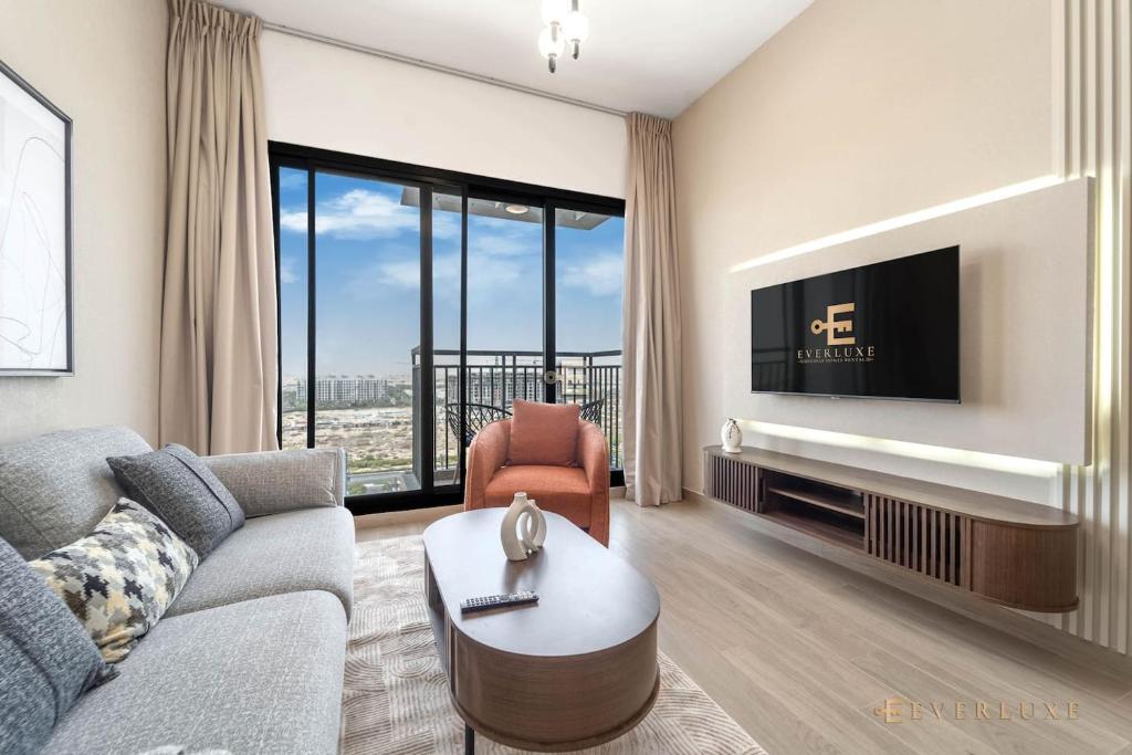 un salon avec un canapé et une télévision dans l'établissement Chic Liva 1br Family-friendly Great Amenities, à Nadd Shubayḩ