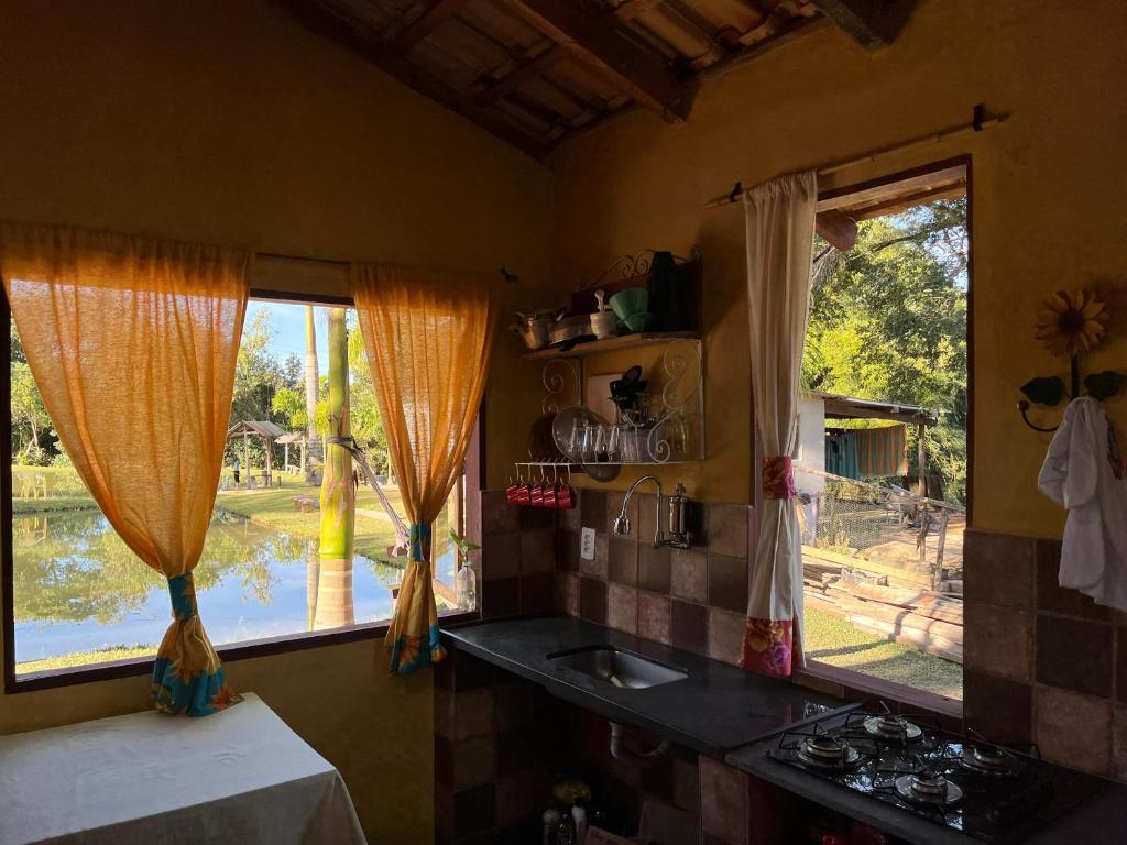 a kitchen with a sink and two windows at Chalé Inhambu Tiradentes in Tiradentes