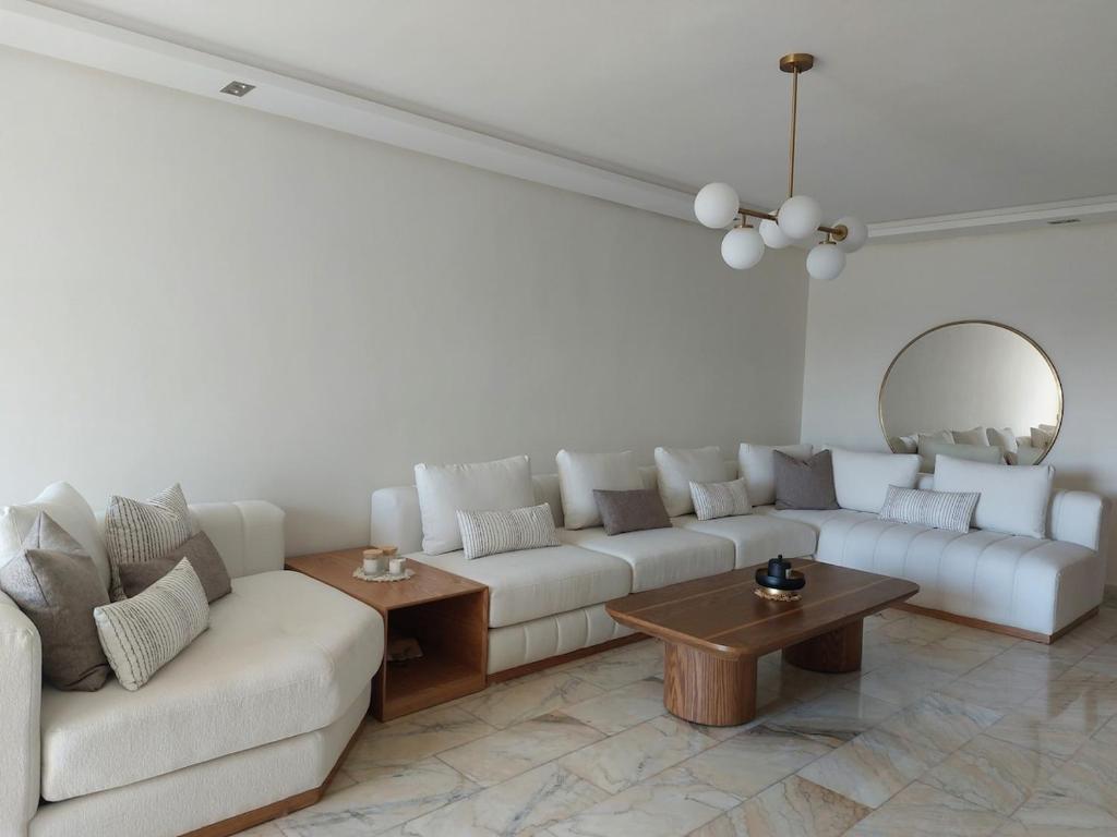 a living room with a white couch and a table at Luxury apartment with sea view and 2 pools Sablettes in Mohammedia