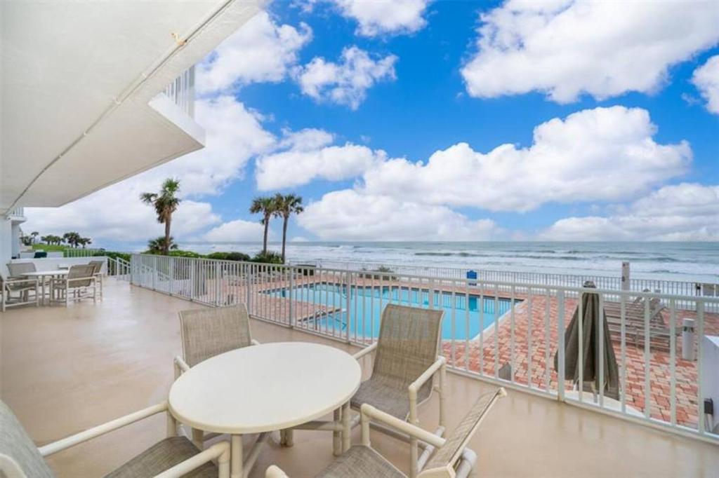 d'un balcon avec une table et des chaises, ainsi que d'une piscine. dans l'établissement Serene 2br Oceanfront Condo With Balcony, Florida, à Ponce Inlet