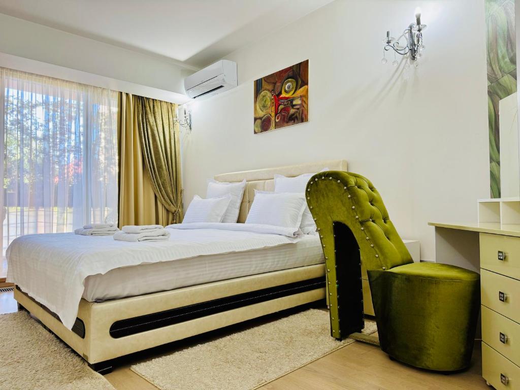 a bedroom with a bed and a green chair at Joy City Stay Memorandului 5 in Timişoara
