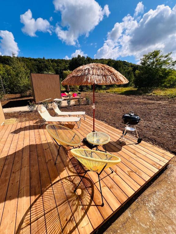 a wooden deck with chairs and an umbrella and a grill at Buddha Cottage - PMR in Rosselange