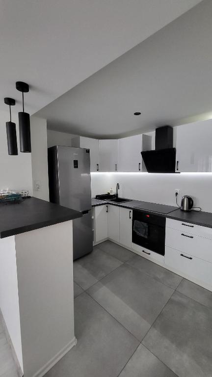a kitchen with white cabinets and a stainless steel refrigerator at Apartament w Lubomierzu in Lubomierz