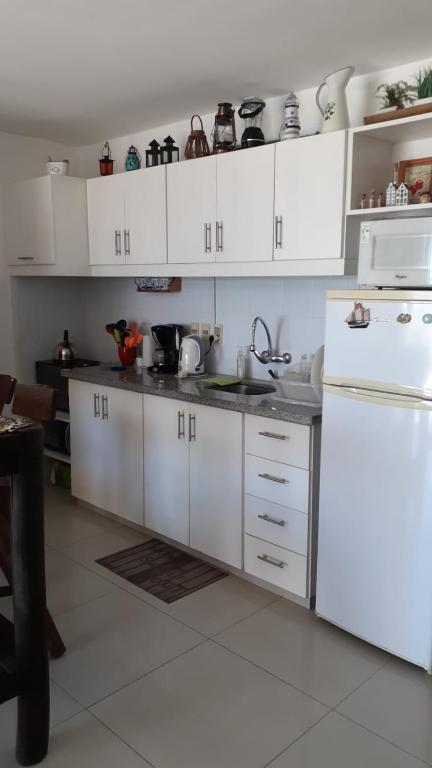 a kitchen with white cabinets and a white refrigerator at Amarras Reales in Piriápolis