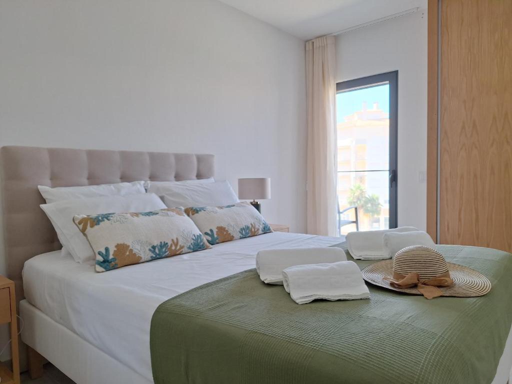 a bedroom with a bed with towels and hats on it at Edifício da Vinha - Ocean Breeze Apartments in Armação de Pêra