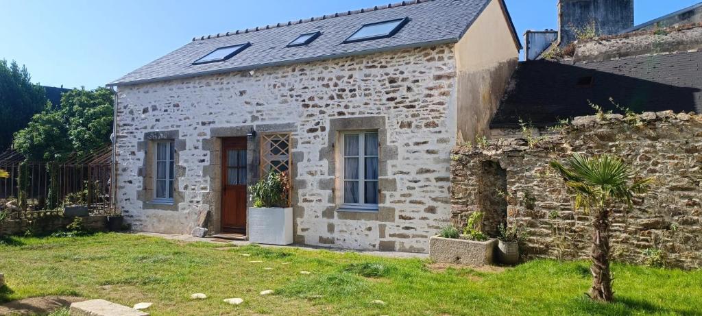 ein altes Steinhaus mit einem Baum davor in der Unterkunft Le Ptit Cottage in Landivisiau