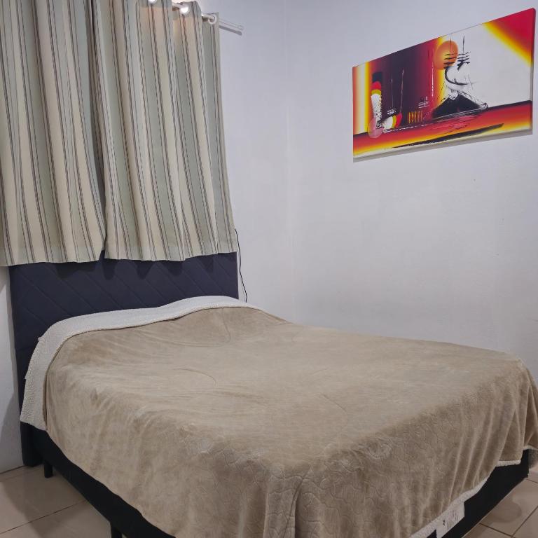 a bed in a room with a window and a curtain at Kyrie Canoinhas Hotel in Canoinhas